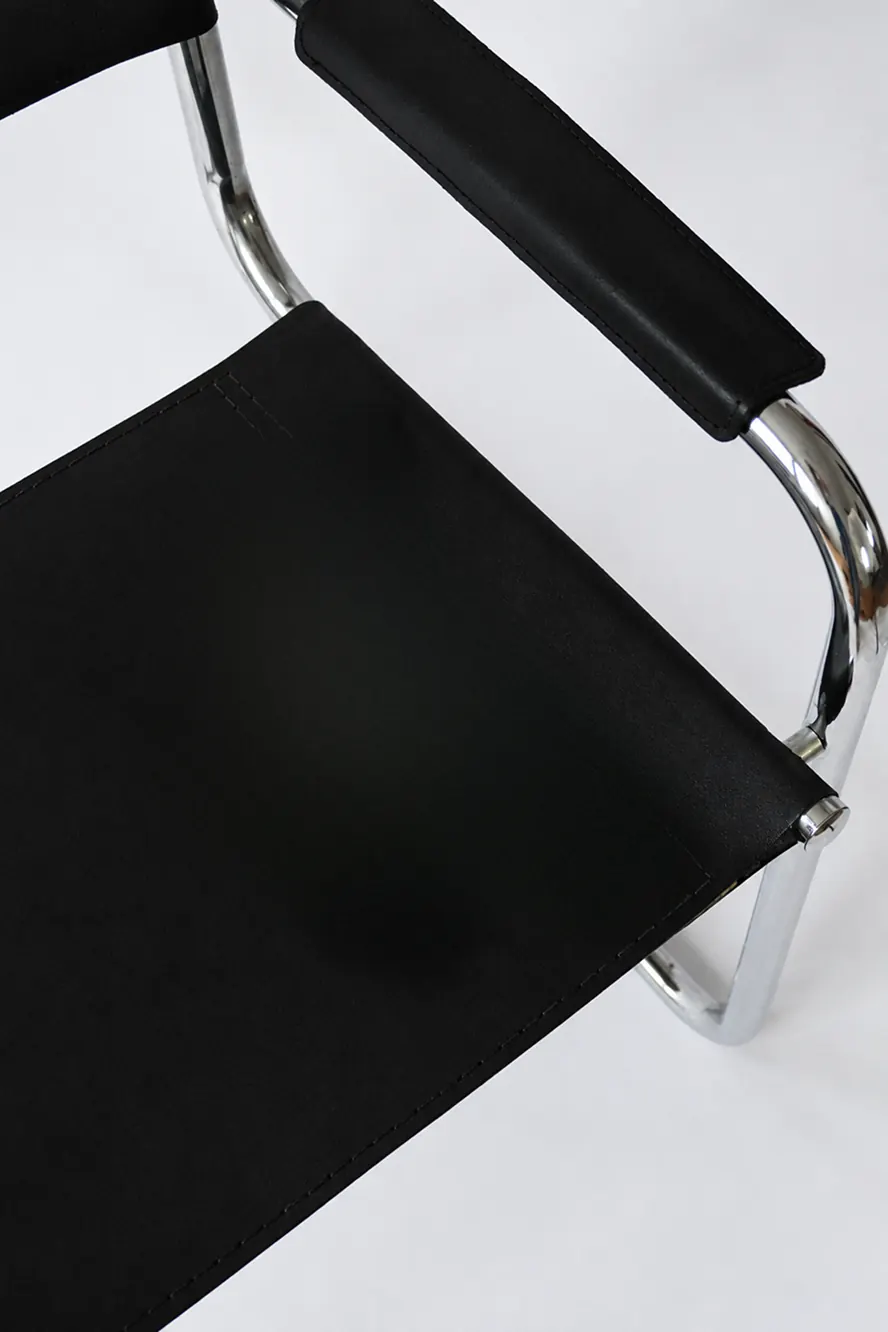 Détail d’un fauteuil en cuir noir et tube chromé
